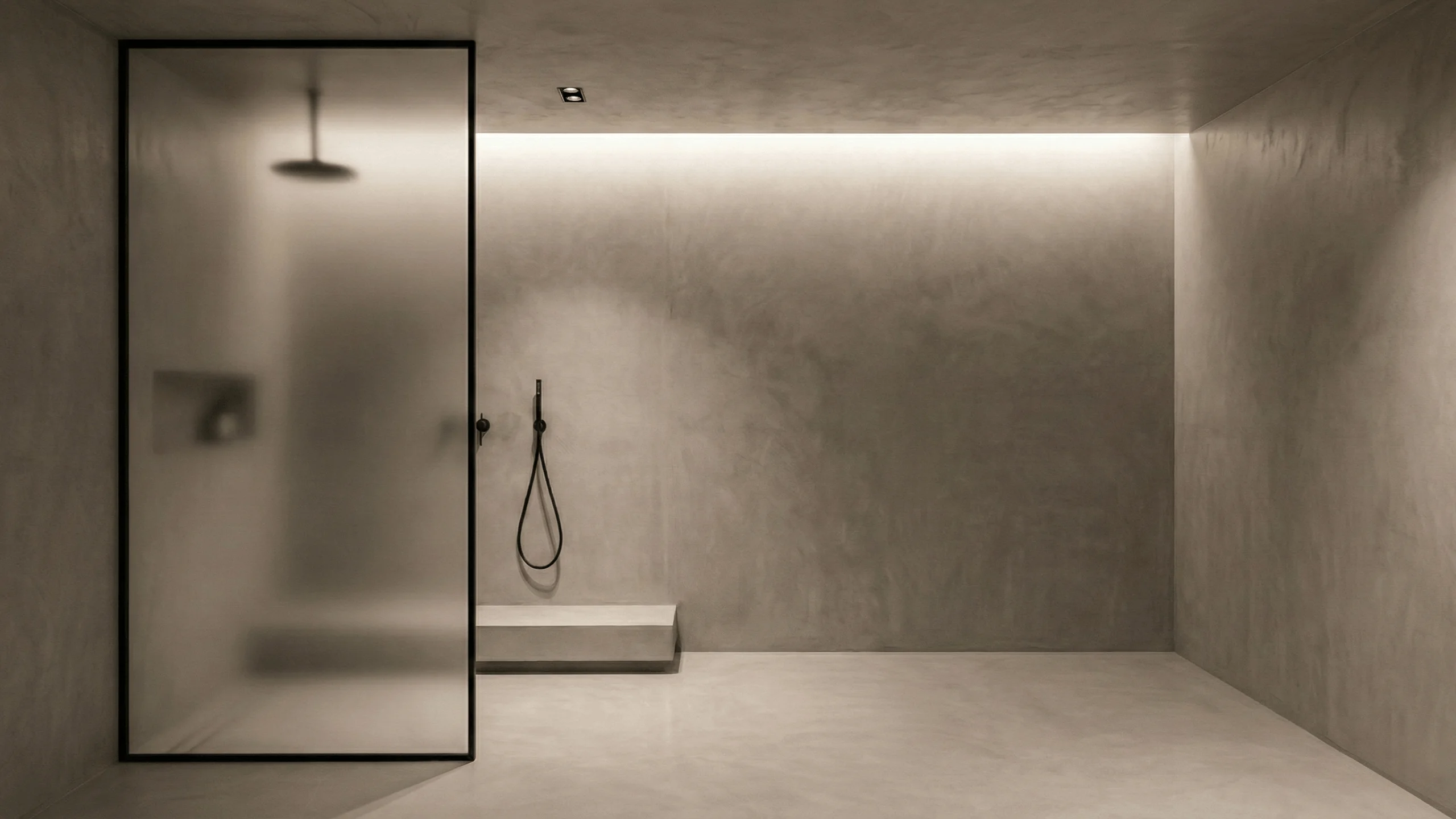 Bagno minimal con doccia walk-in, pareti, pavimento e soffitto rivestiti in microcemento grigio continuo, grande vetro satinato e illuminazione LED diffusa.